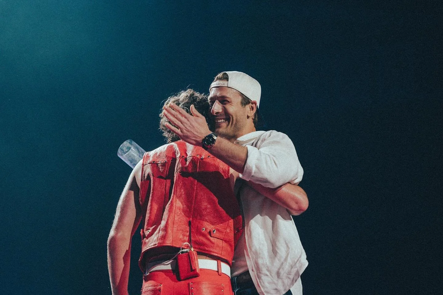 Benson Boone embracing actor Glen Powell at the Moody Center in Austin, Texas