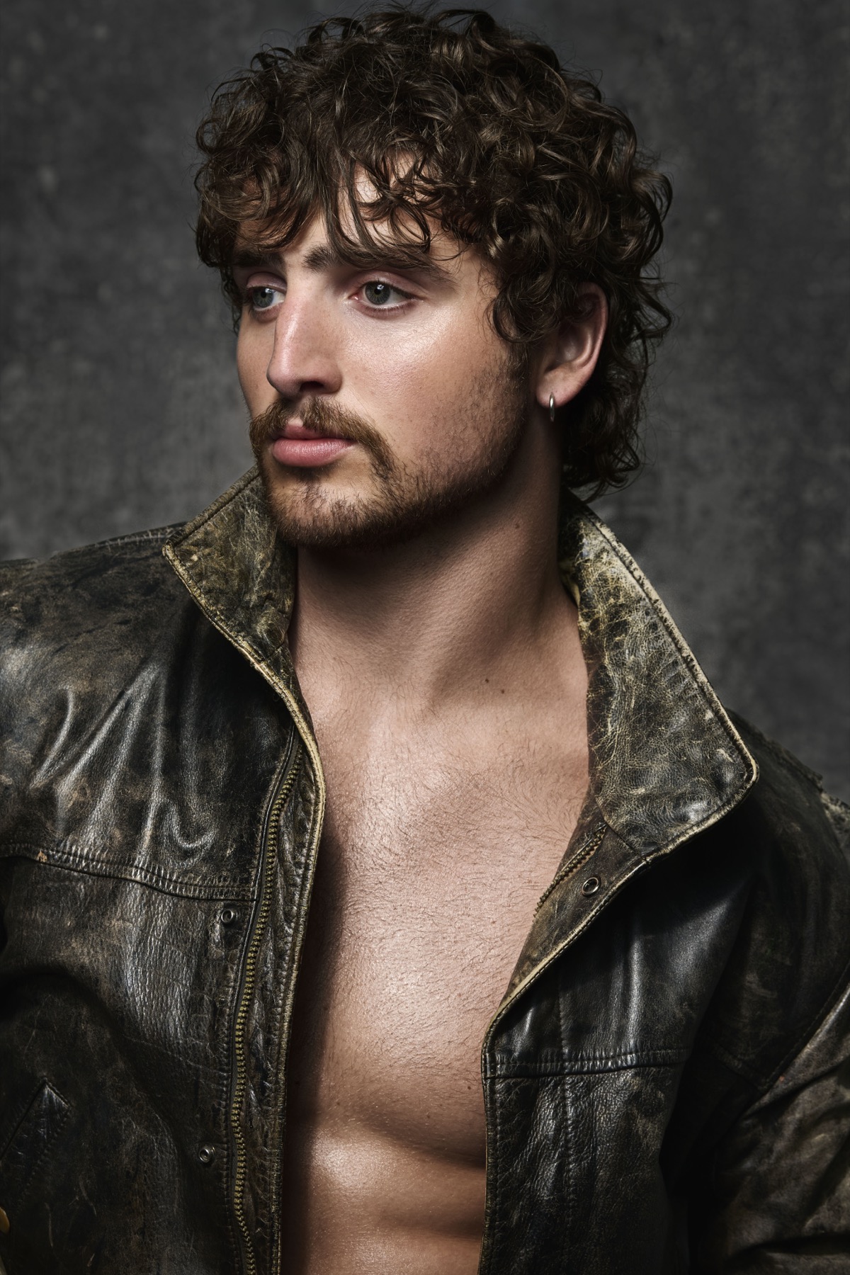 Benson Boone wearing a weathered leather jacket in a 2026 studio portrait