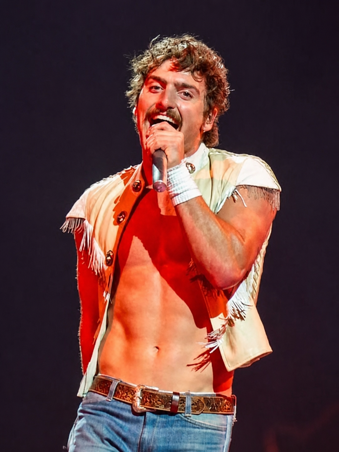 Benson Boone singing in a fringed white vest on the Wanted Man Tour in 2026